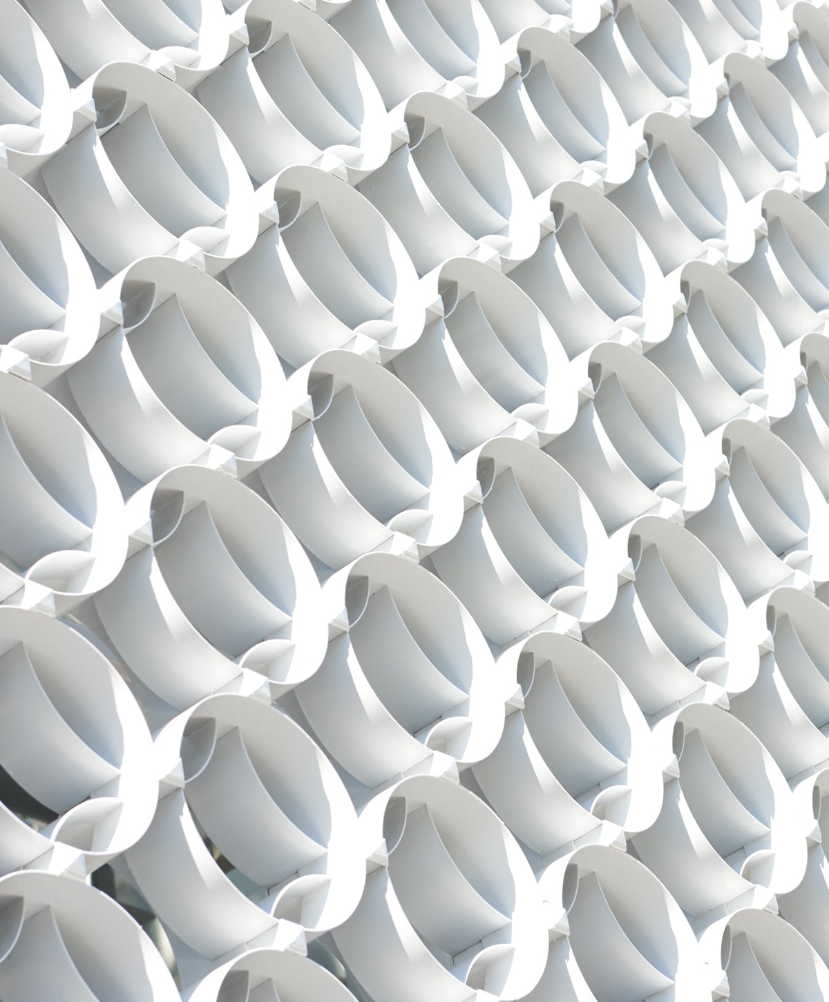 Close-up of a geometric pattern featuring overlapping white cylinders in rows, forming a repeating 3D effect with shadows and highlights.