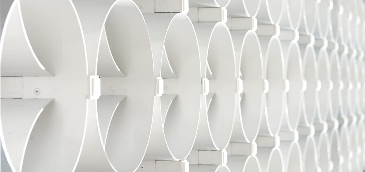 Close-up of a modern architectural wall with repeating circular cut-outs and geometric patterns in a white minimalist style.